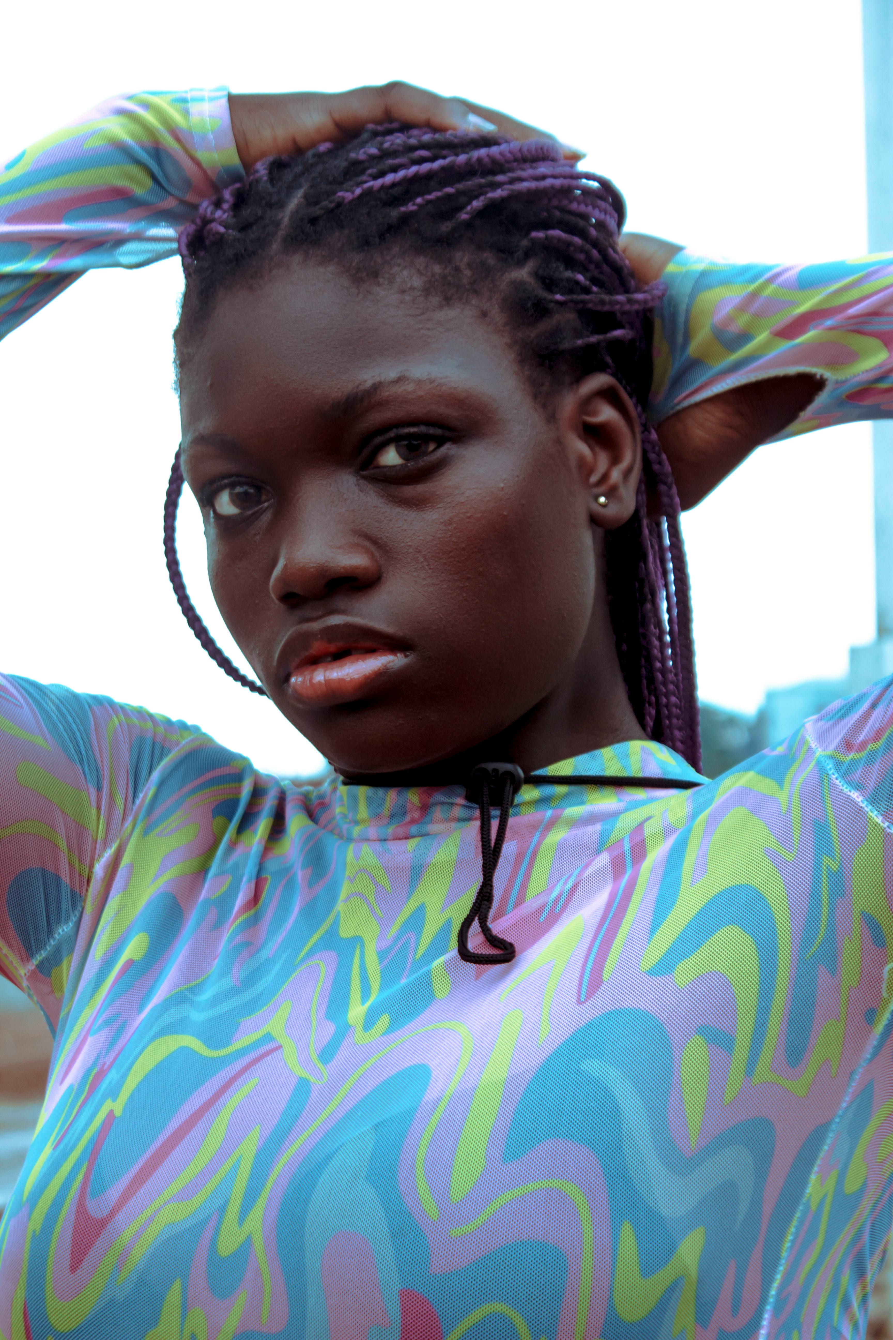 Stylish portrait of a woman with braided hair in a colorful patterned blouse, outdoors.