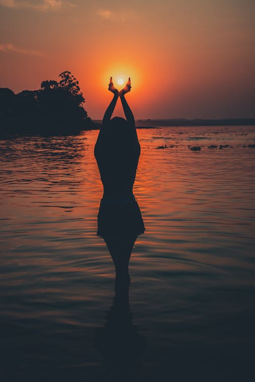 Silhouette of Woman Standing on Water during Sunset