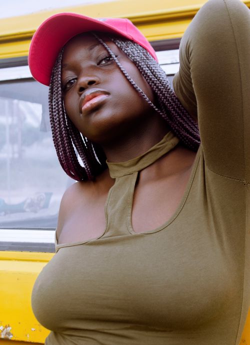 Free Fashionable African American woman in a pink cap posing confidently outdoors. Stock Photo