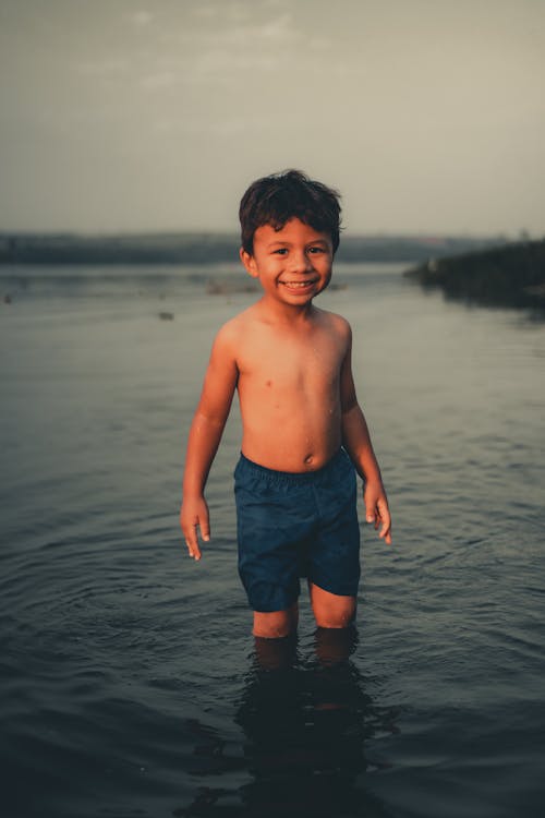 A Shirtless Boy Wearing Blue Shorts Standing on Water