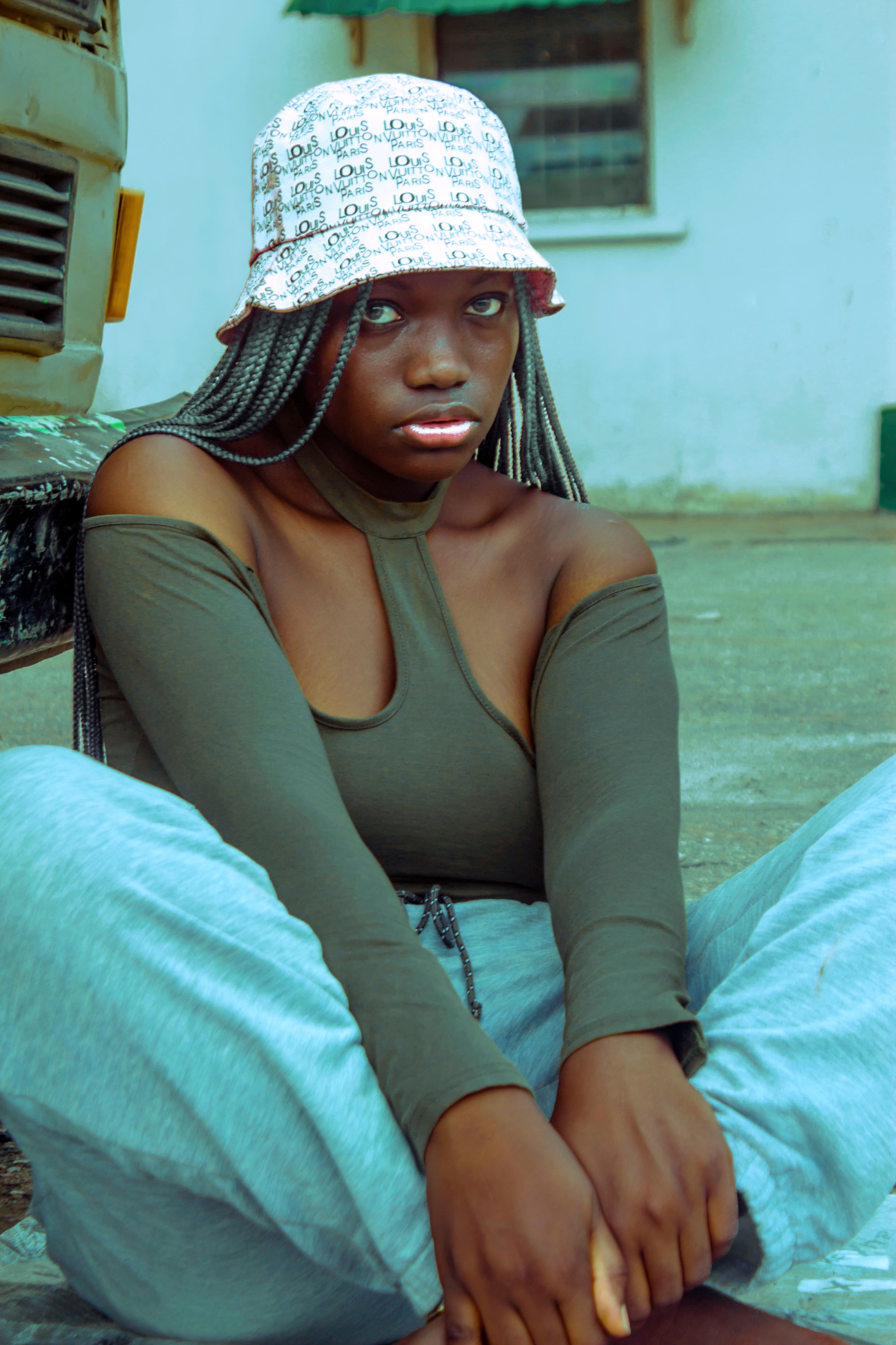 Casual portrait of a young woman in relaxed attire with a bucket hat, sitting outdoors.