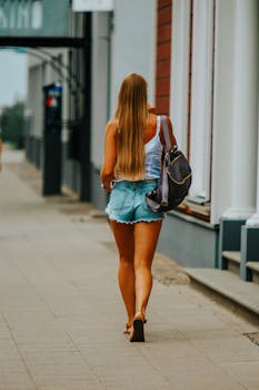 A woman walking on a city street in Riga, Latvia wearing casual summer attire and a backpack.