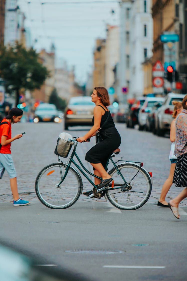 Woman Riding Bicycle Across Street