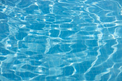 Free Close-up shot of rippling water texture in a swimming pool on a sunny day. Stock Photo
