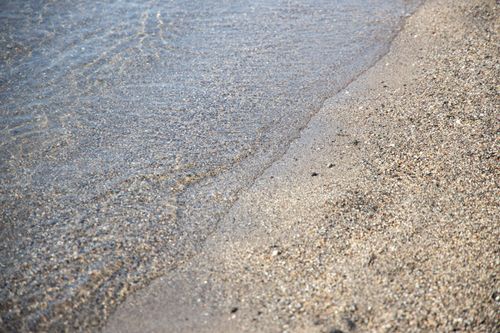 Free Close-up of a tranquil beach with gentle waves lapping at the sandy shore. Stock Photo