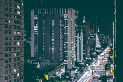 Free Dynamic night view of a bustling city street with skyscrapers and light trails creating motion. Stock Photo