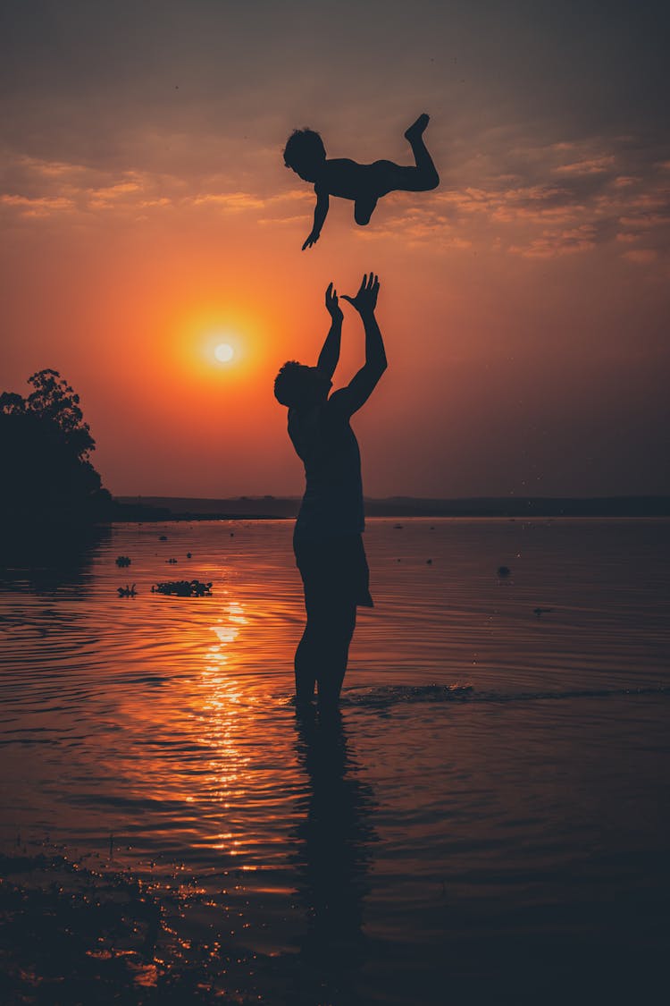 Silhouette Of A Man With A Boy And Sea At Sunrise 