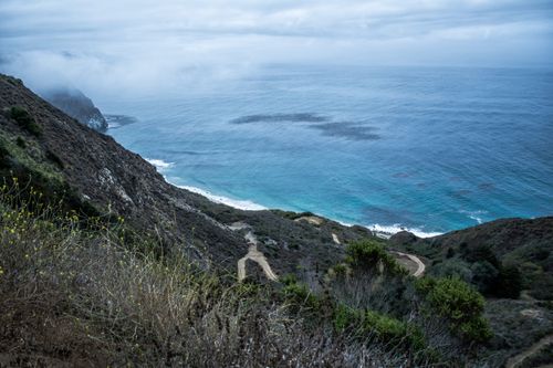 Free A breathtaking view of rugged cliffs and the ocean, enveloped in mist. Stock Photo