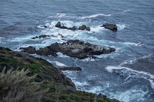Free A serene view of rocky coastline with waves crashing onto rocks, showing natural beauty. Stock Photo