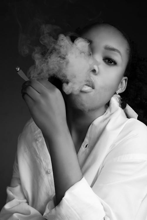 Black woman smoking cigarette and exhaling smoke