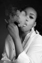 Black woman smoking cigarette and exhaling smoke