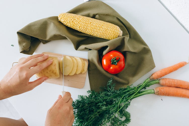 A Person Slicing A Potato