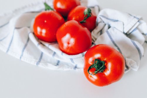 Free Close-up of fresh red tomatoes resting on a white and blue striped cloth. Stock Photo