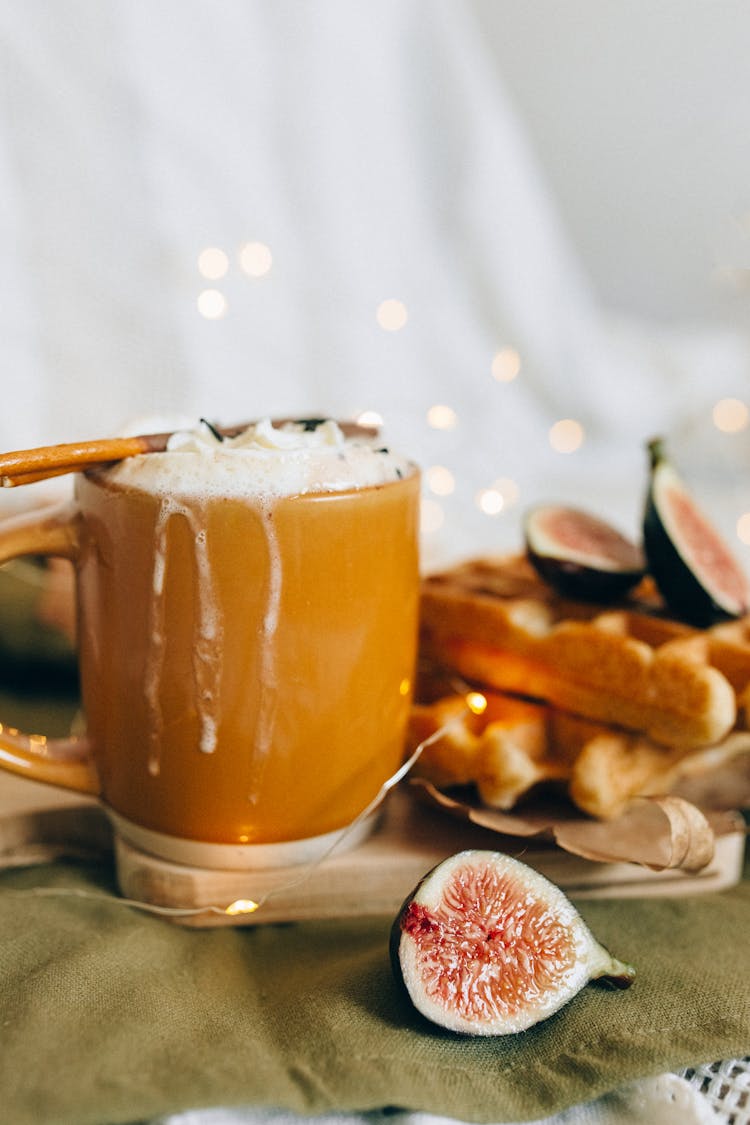 A Brown Mug With A Frothy Drink Beside A Sliced Fruit