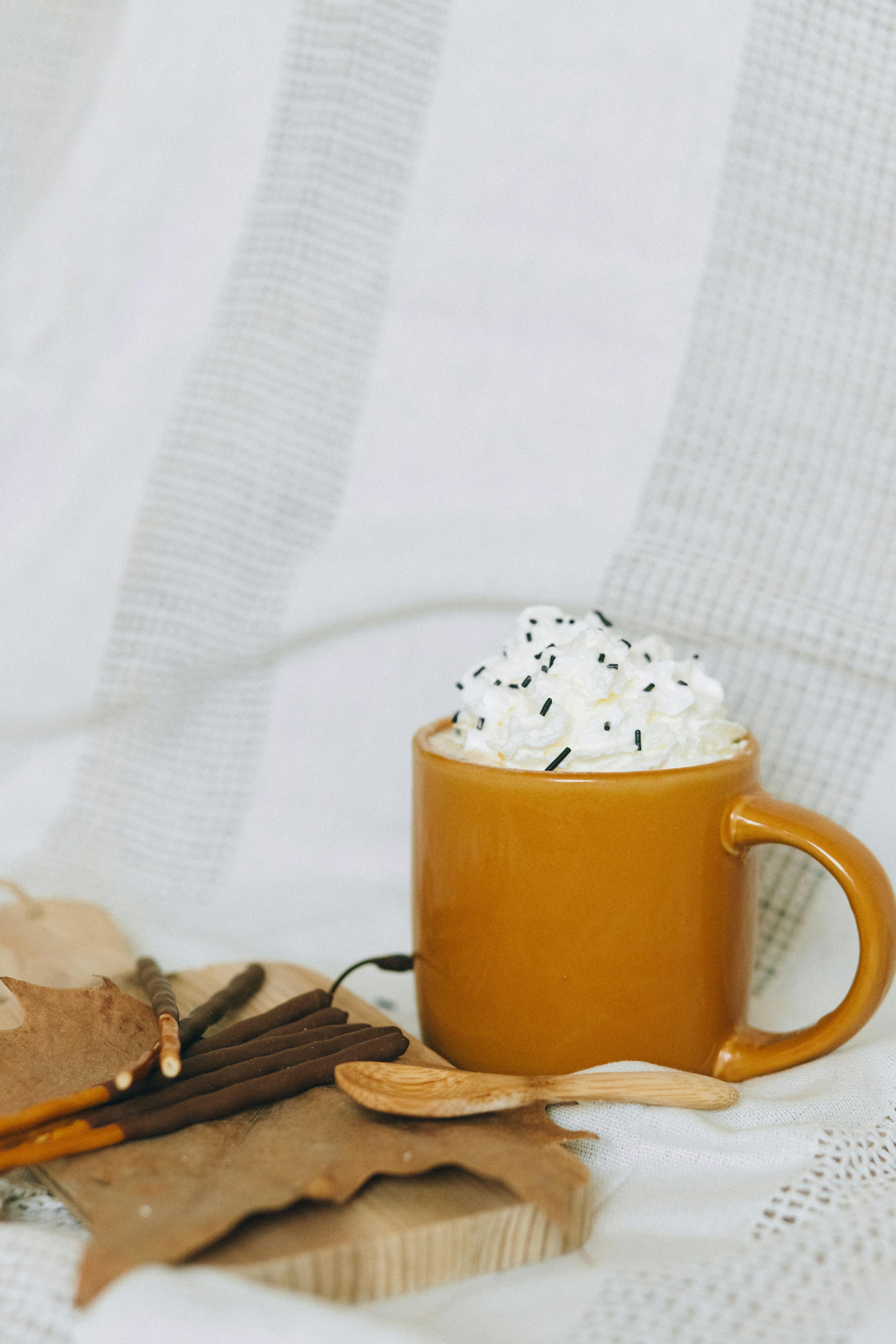 这款温暖的黄色马克杯，涂着鲜奶油，衬着舒适的织物背景，非常适合用于食品摄影