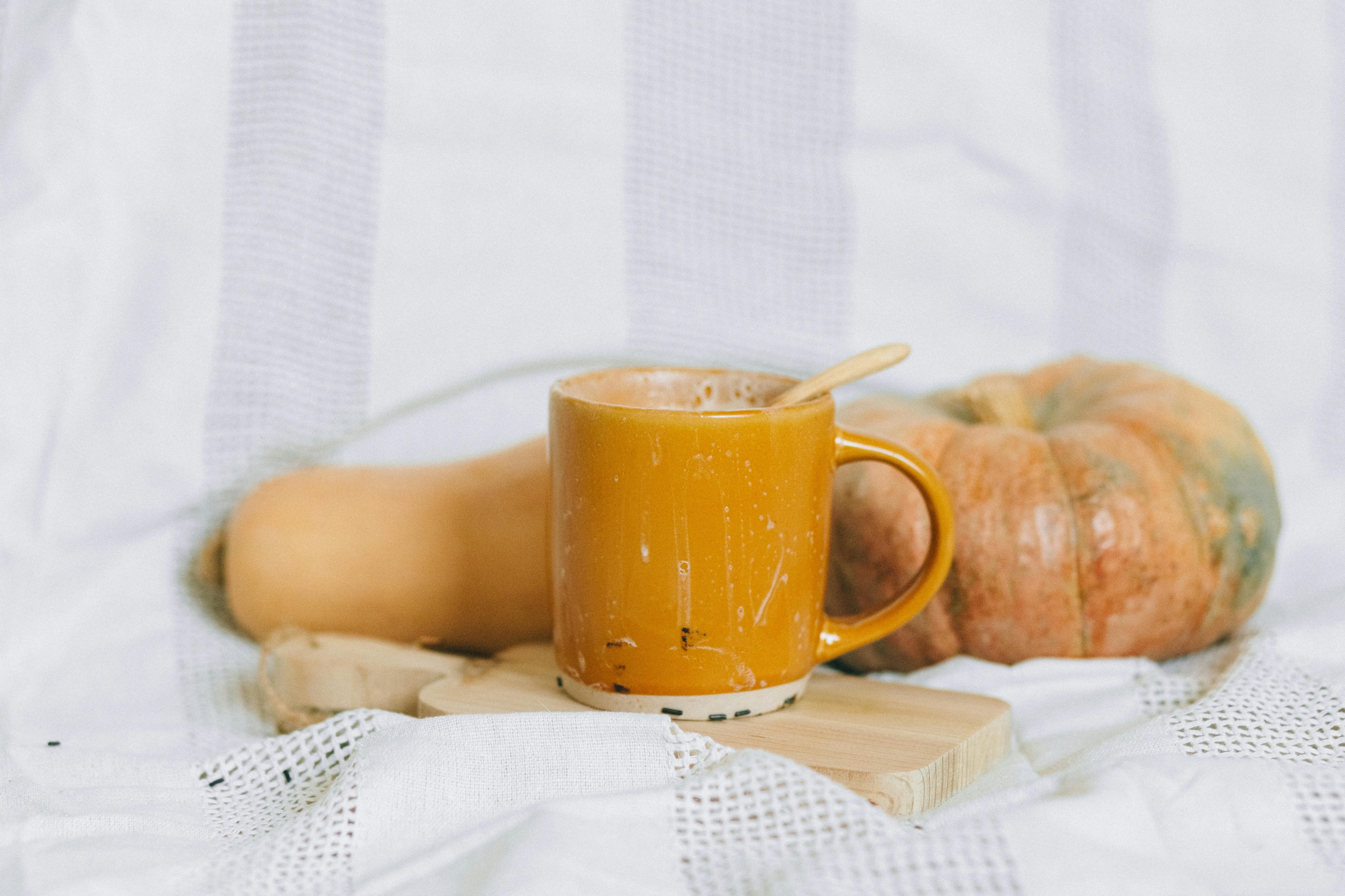 yellow ceramic mug on white textile