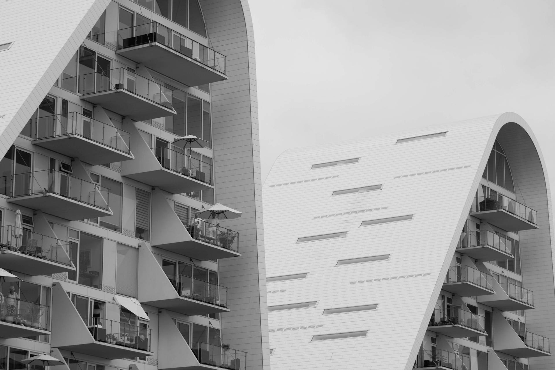 Futuristic curved residential building with glass balconies and sleek design.