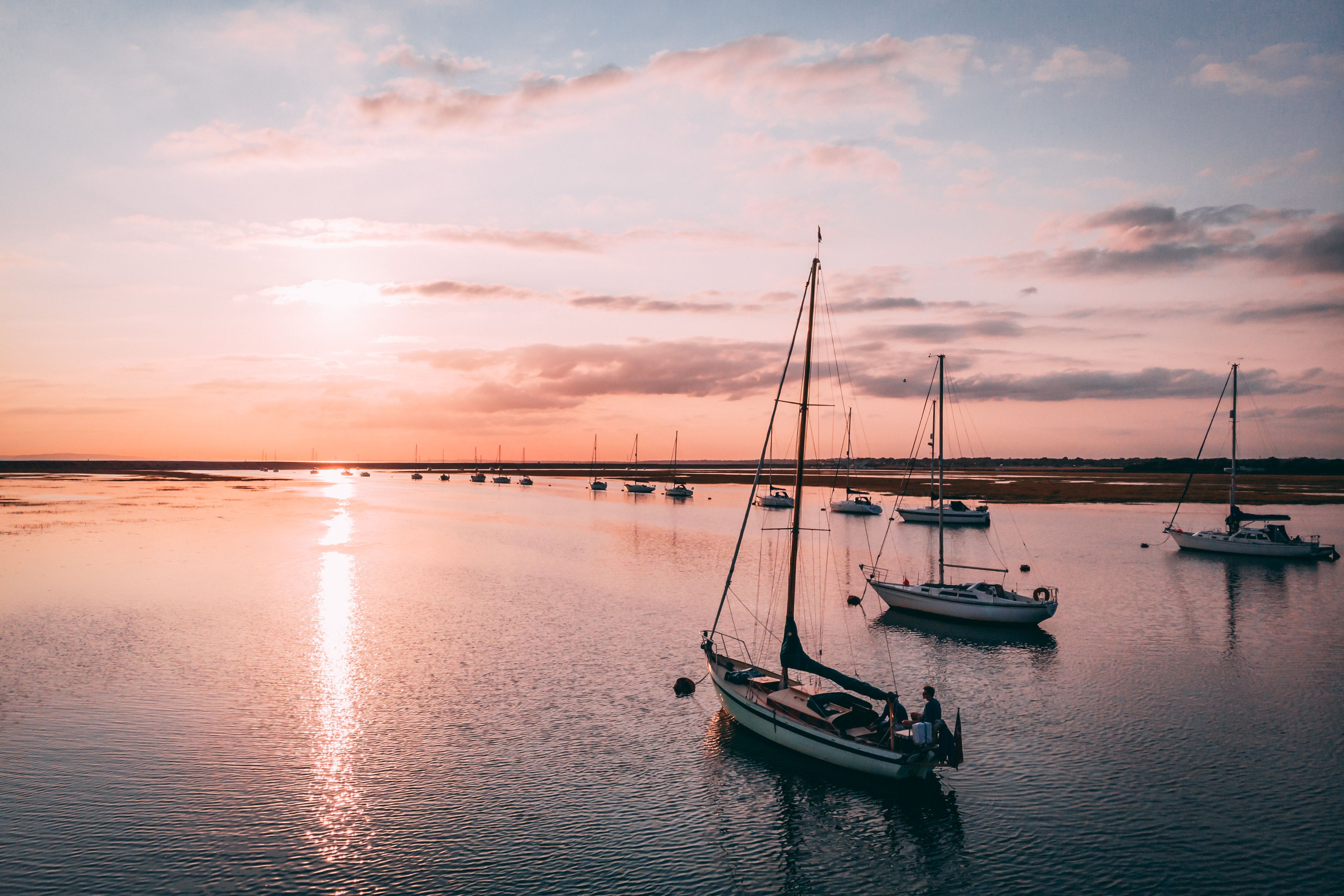 A serene scene of sailboats in Milford on Sea at sunset, capturing the tranquil ocean ambiance.