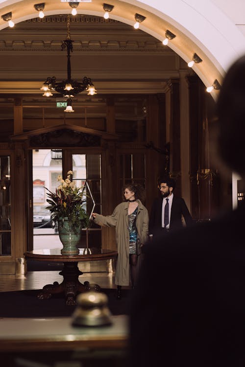 Man and Woman Standing in a Hotel Lobby Looking at a Flower Vase Decoration