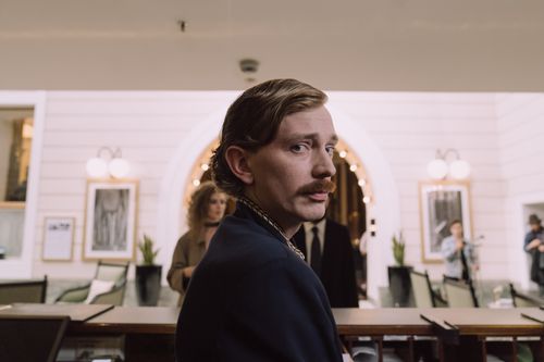Free Hotel concierge at the front desk with a classic ambiance in the background. Stock Photo