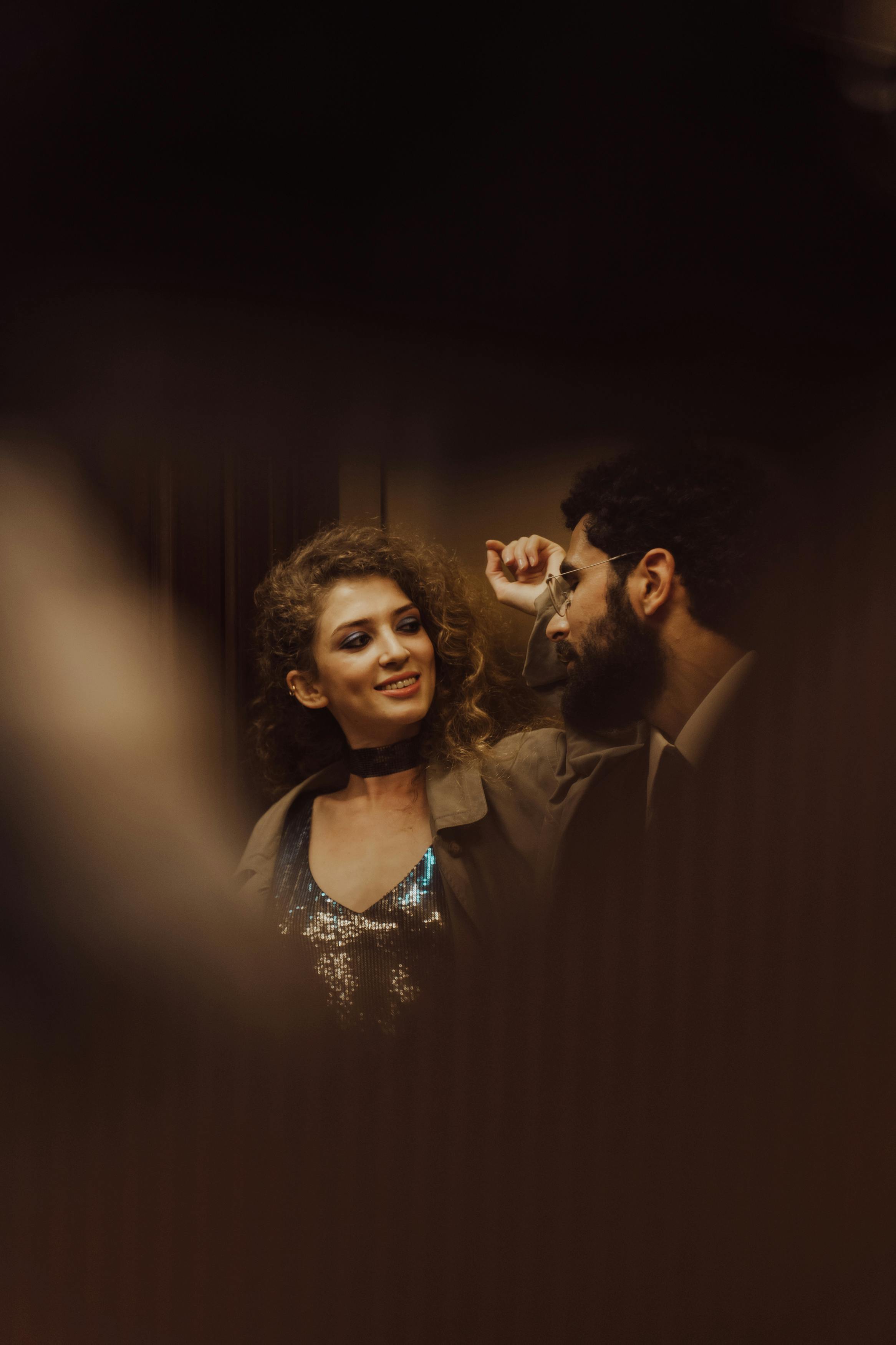 man and a woman standing inside an elevator looking at each other