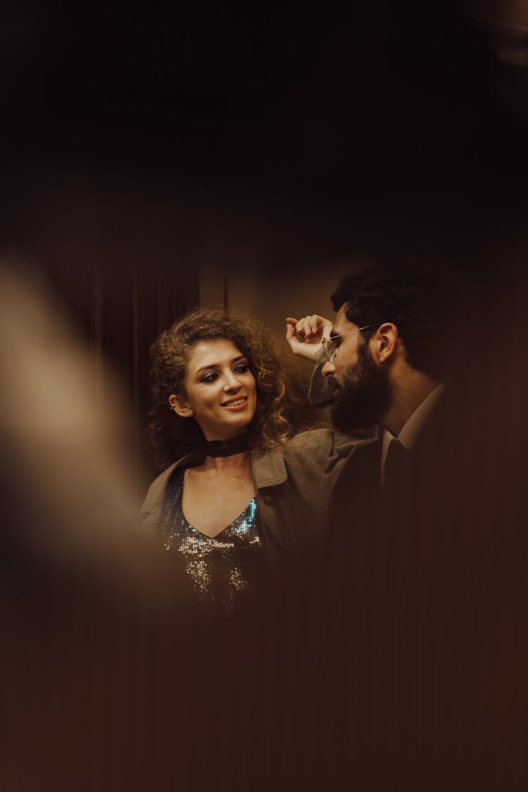 Man And A Woman Standing Inside An Elevator Looking At Each Other