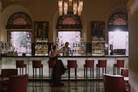 一名身穿黑色连衣裙的女子正在一家时尚豪华的酒吧里与调酒师交谈