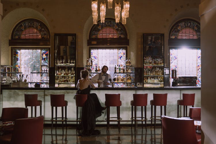 Woman In Black Dress Sitting Alone At A Bar Counter