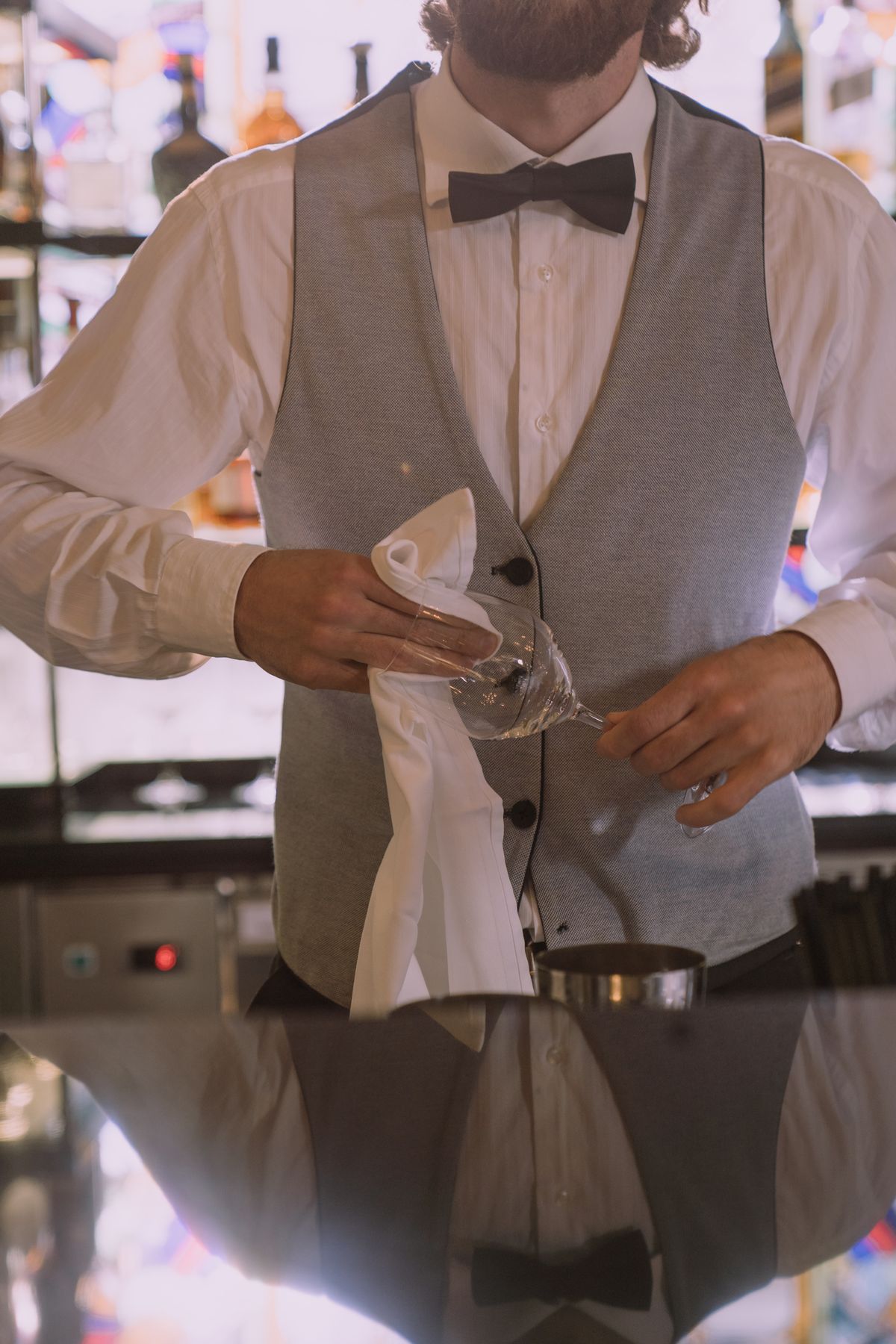 A bartender polishing a wine glass with a cloth to a streak-free, lint-free shine