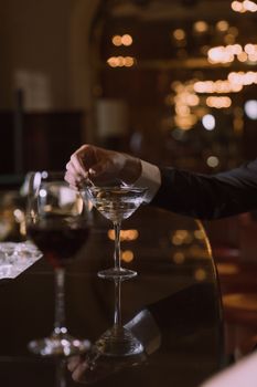 在一家灯光昏暗、散景朦胧的酒吧里，一只优雅的手正握着马提尼杯