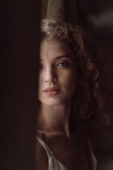 这幅肖像画描绘了一位卷发半掩的女性，显得神秘而优雅