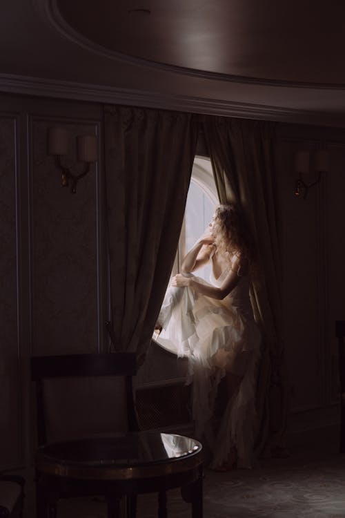 Woman in White Dress Sitting Near a Window