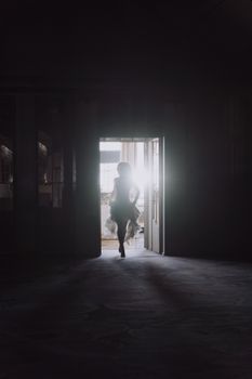 一名身穿飘逸婚纱的女子剪影穿过门口，在明亮灯光下形成了戏剧性的对比