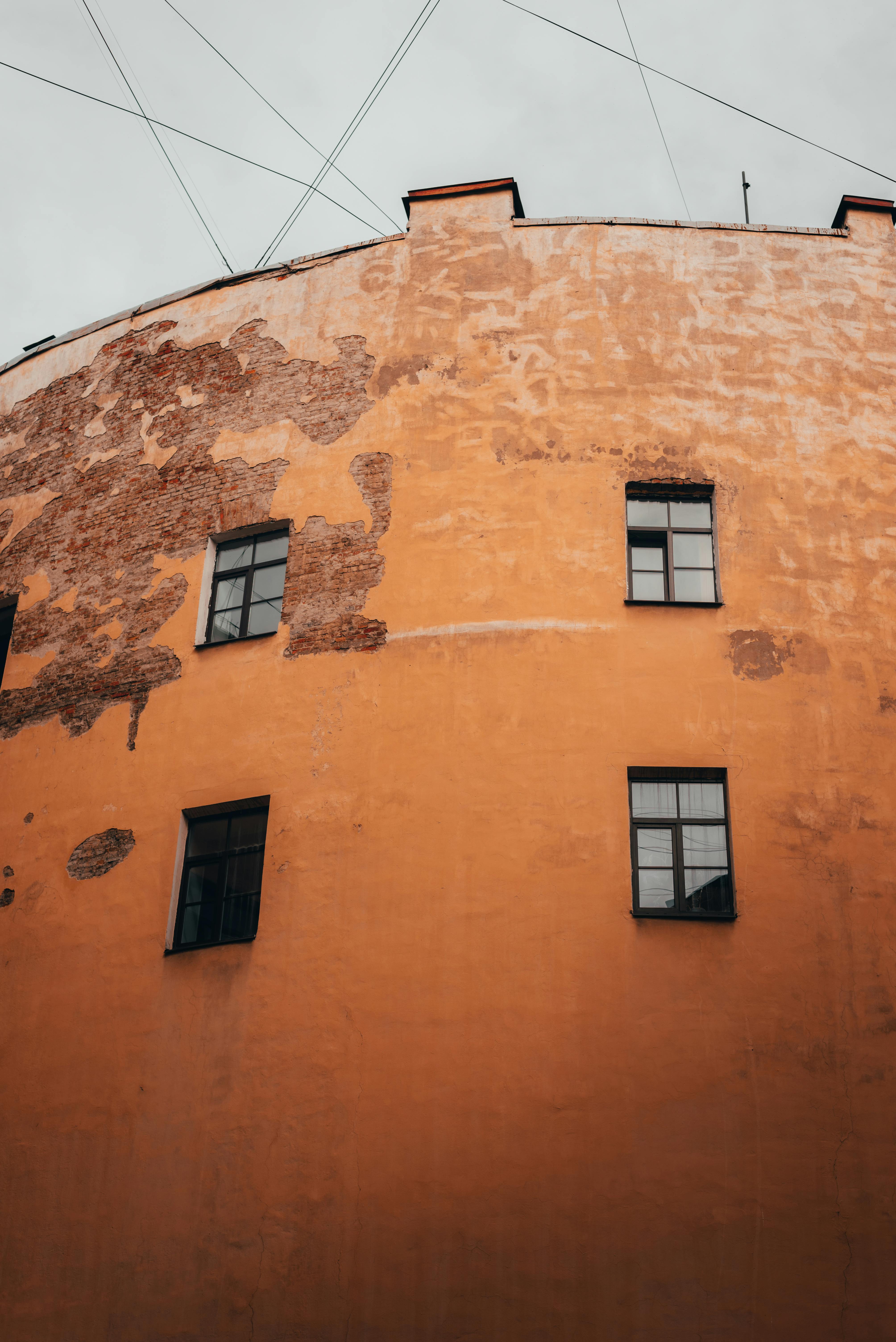 A weathered orange building facade with windows, showcasing urban decay.