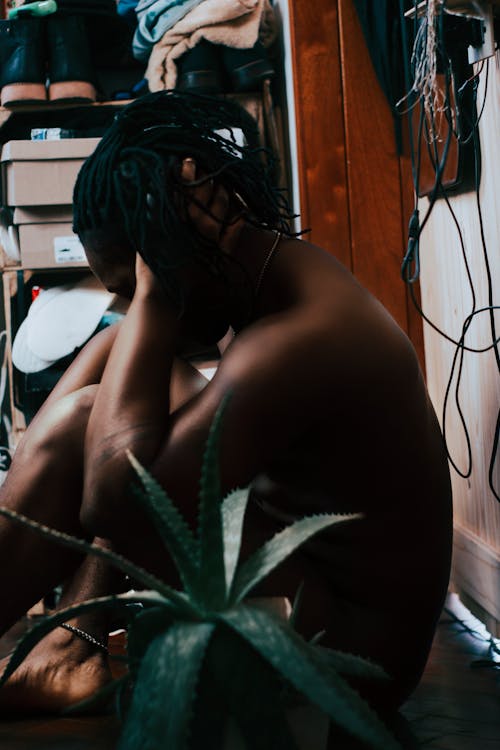 A Topless Person Sitting near a Succulent Plant