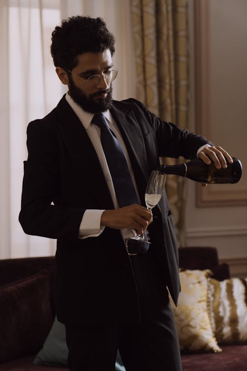 Man in Black Suit Pouring Champagne in a Glass