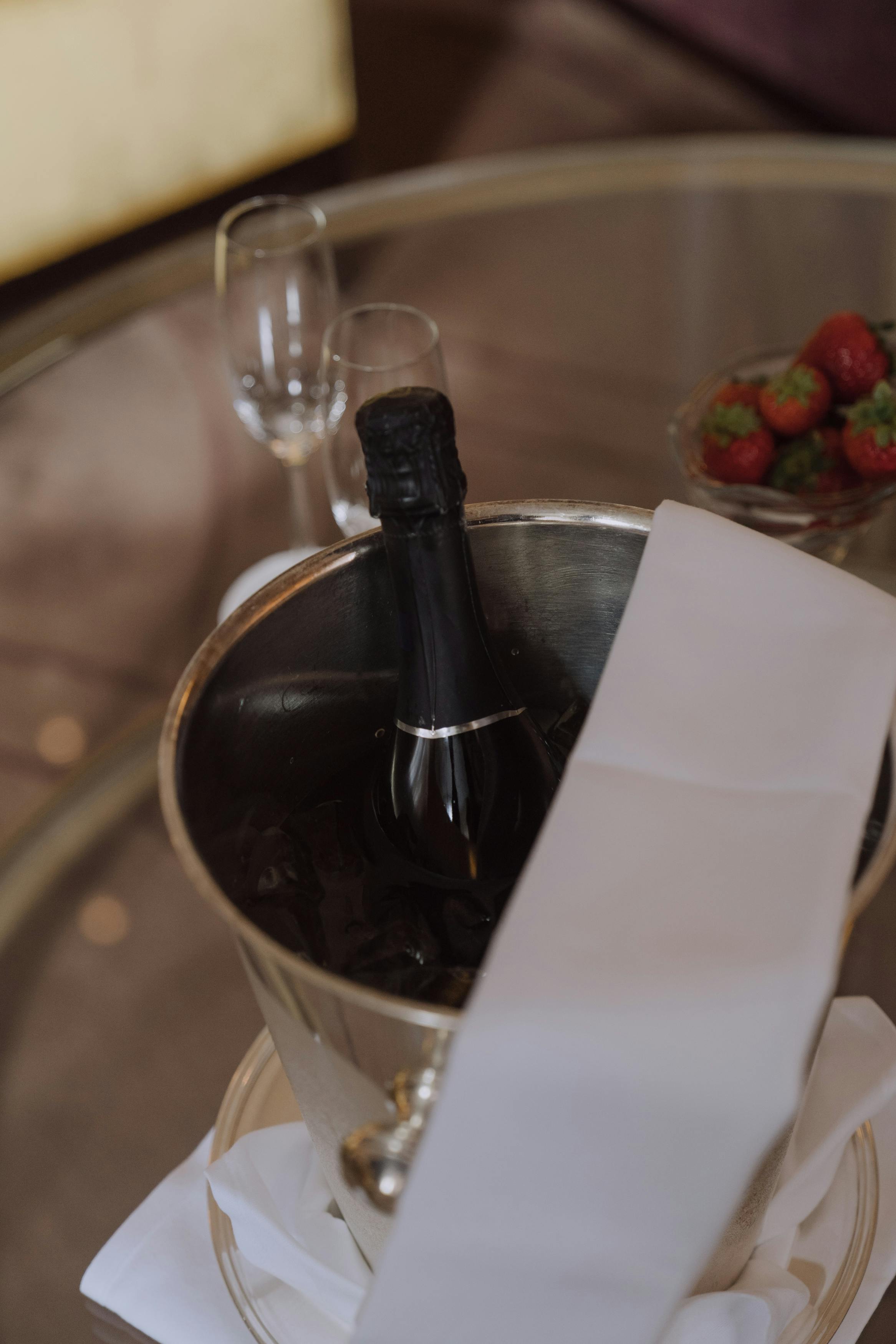 Elegant setting with champagne bottle and strawberries on a glass table, perfect for celebrations.