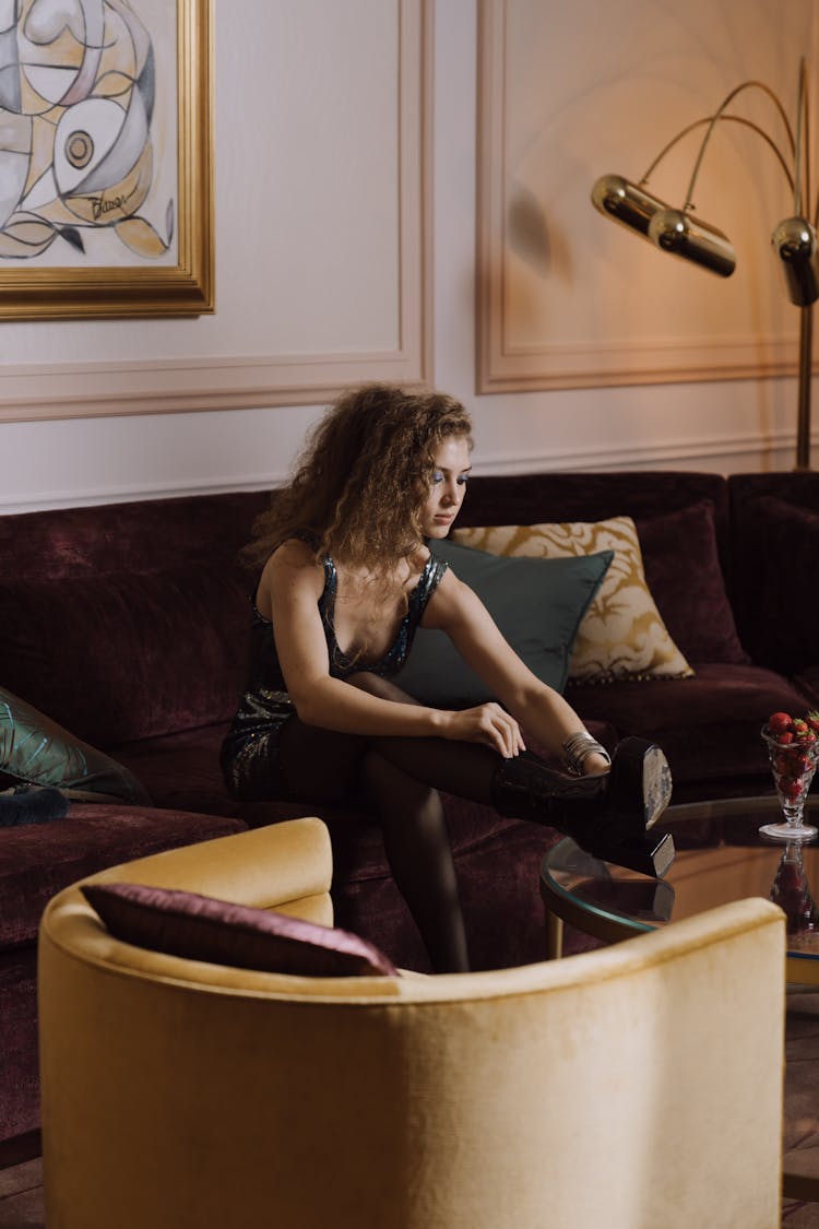 Woman Sitting On Sofa Putting In Boots