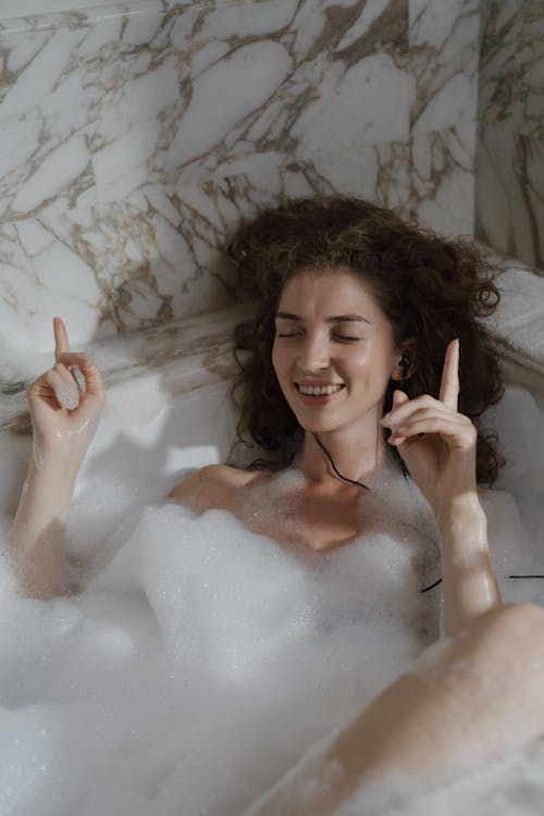 Woman Taking Bath in a Bathtub while Listening to Music