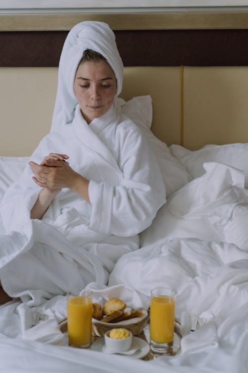 Free Woman in Bathrobe Sitting on Bed  Stock Photo