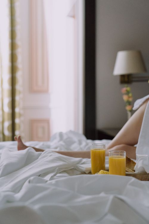 Free Relaxing morning with orange juice and breakfast tray on a bed, capturing a serene lifestyle moment. Stock Photo