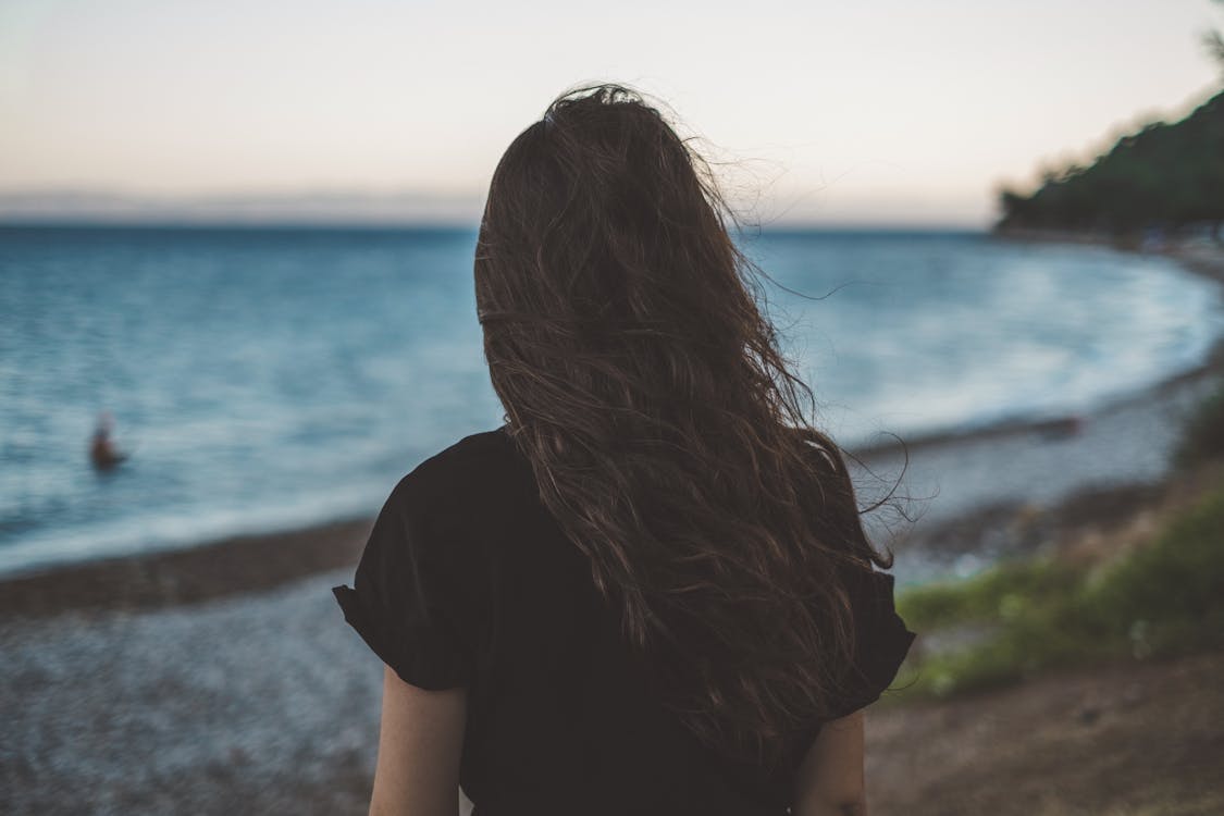 Back View of Woman in Black T-shirt Standing Near Sea · Free Stock Photo