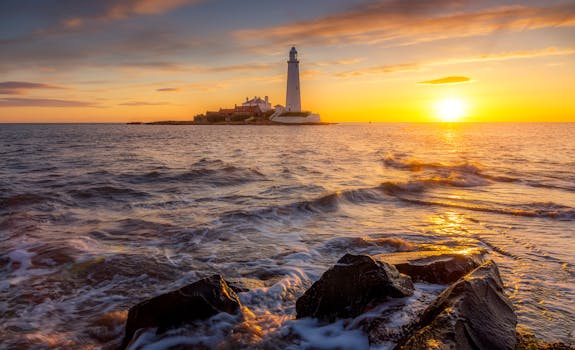 Scenic view of a lighthouse during sunrise with ocean waves and rocky shore.