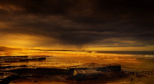 Body of Water Under Dark Clouds during Sunset 