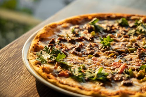 Free Close-Up View of a Pizza on Brown Wooden Table Stock Photo