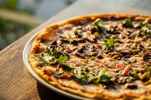 Free Close-up of a mouthwatering Italian-style pizza with a variety of toppings in warm lighting. Stock Photo