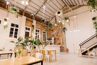 Amazing view of creative interior of restaurant decorated with gold garland and green potted flowers on floor