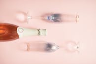 粉红色背景前，香槟瓶与两个玻璃杯风格优雅，非常适合庆祝活动和聚会