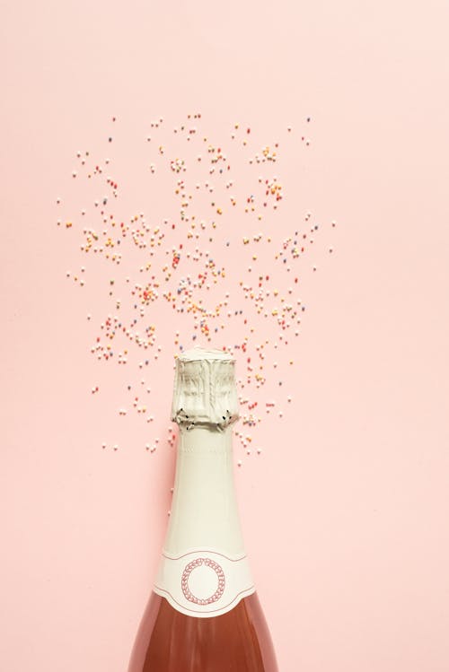 A Champagne Bottle Against a Light Pink Background