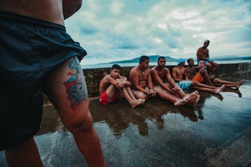 Unrecognizable tattooed man near multiracial friends on embankment
